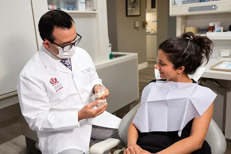 Dr. Pooya Soltanzadeh explaining a dental model to a smiling patient